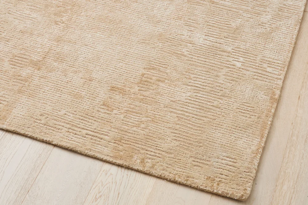 Oat-colored hand-woven wool rug with a textured design, perfect for adding warmth and style to living spaces.